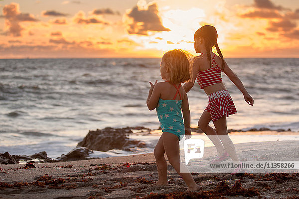 Mädchen und Schwester laufen bei Sonnenaufgang am Strand  Blowing Rocks Preserve  Jupiter Island  Florida  USA