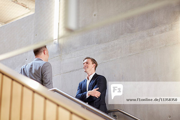 Zwei Geschäftsleute unterhalten sich auf einer Bürotreppe