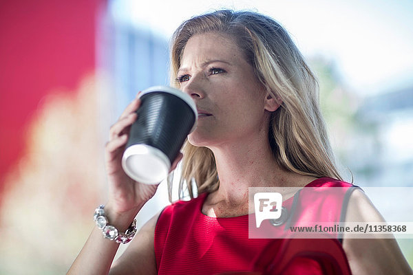 Geschäftsfrau trinkt Kaffee zum Mitnehmen in der Stadt