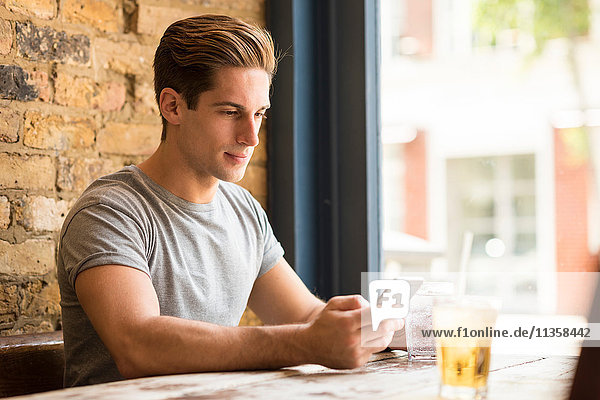 Young man reading smartphone text in bar