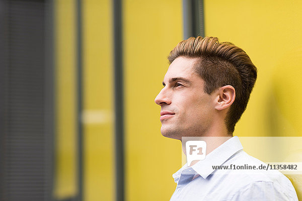 Portrait of young businessman leaning outside office  London  UK