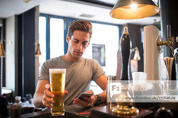 Young man reading smartphone at city bar