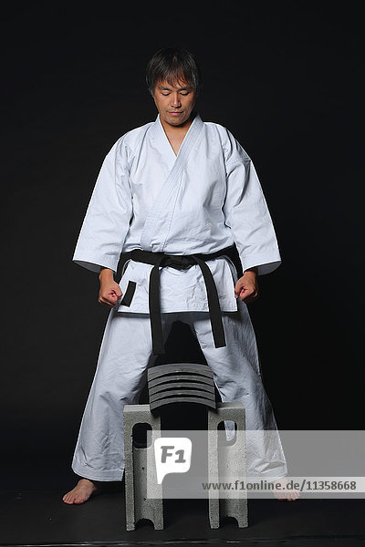 Japanischer Karatemeister konzentriert sich vor dem Zerbrechen von Fliesen