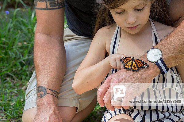 Vater und Tochter betrachten den Monarchfalter