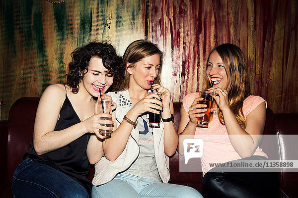 Three adult female friends drinking in bar