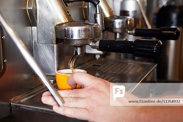 Male worker in bakery  using coffee machine  close-up
