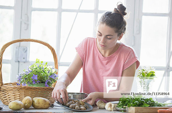 Junge Frau beim Zubereiten von Schnecken an der Küchentheke  Vogogna  Verbania  Piemont  Italien