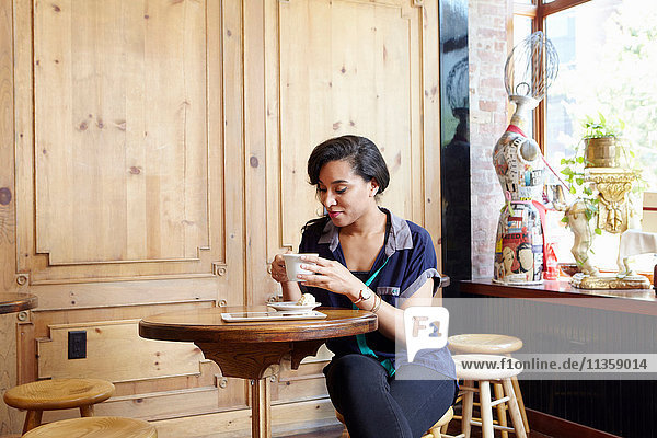 Junge Frau sitzt im Café und trinkt Kaffee