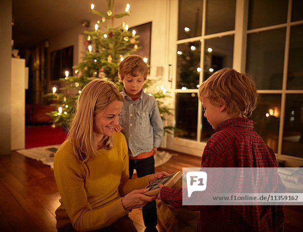 Mutter und Söhne sitzen zu Weihnachten zu Hause und tauschen Geschenke aus