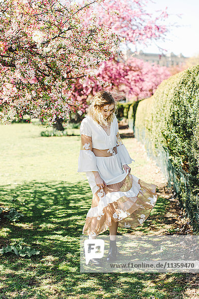 Frau im Garten am Kirschbaum wirbelndes Kleid