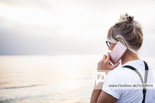Woman by ocean making telephone call on smartphone  Encinitas  California  USA