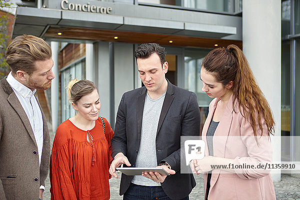 Businesswomen and businessmen looking at digital tablet outside office  London  UK