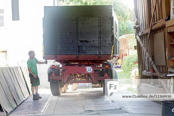 Männlicher Landwirt entriegelt Erntewagen in Scheune