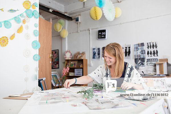 Female designer preparing mixed media design in printing press studio
