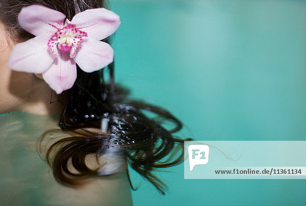 Schnappschuss einer Frau im Whirlpool mit violetter Orchidee im Haar