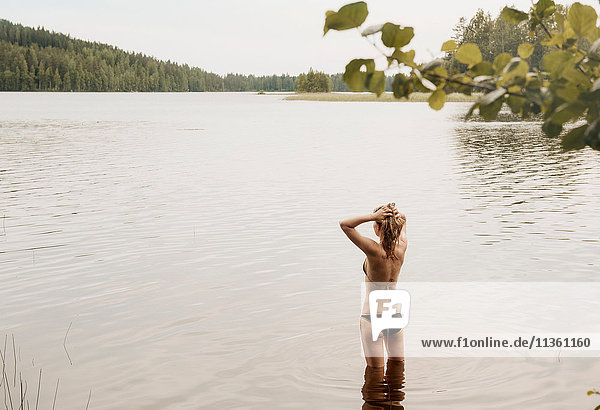 Rückansicht einer Frau mit Händen im Haar im See  Orivesi  Finnland