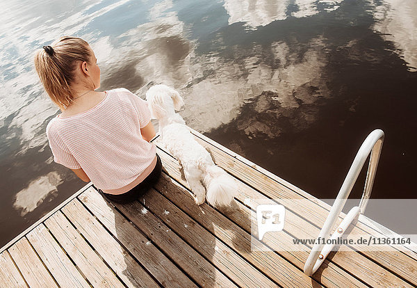 Frau sitzt mit dem Hund Coton de tulear am Seepier  Orivesi  Finnland