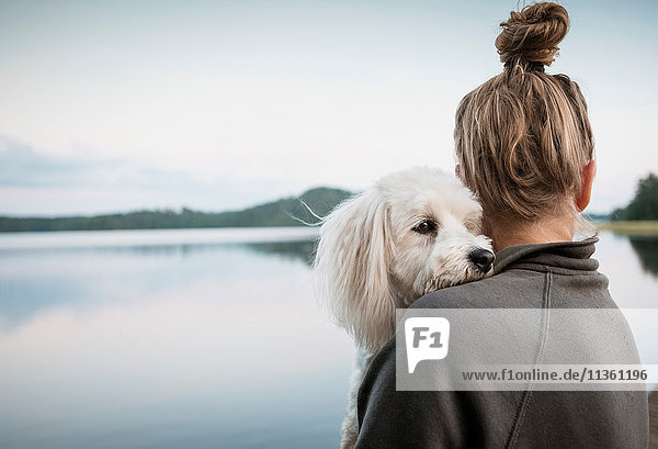 Coton de tulear Hund schaut über die Schulter der Frau am See  Orivesi  Finnland