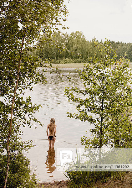 Rückansicht einer Frau  die steht und vom See aus schaut  Orivesi  Finnland