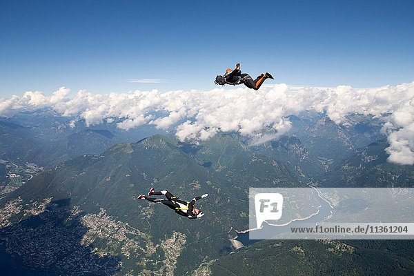 Freestyle Skydiving Team trainiert gemeinsam. Ein Mann führt Luftballett auf  ein anderer Springer filmt mit Videokamera am Helm  Locarno  Tessin  Schweiz
