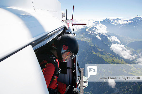 Female sky diver in helicopter checking for exit over mountain  Interlaken  Berne  Switzerland