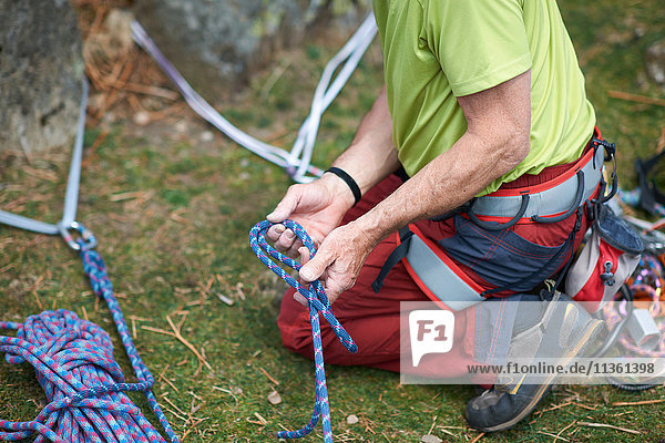 Schrägansicht eines Felskletterers  der ein Kletterseil vorbereitet