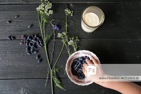 Draufsicht auf Jungen die mit der Hand Beeren aus einer Schüssel aufsammeln