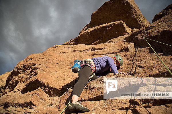 Female rock climber climbing mountain  low angle view  Smith Rock State Park  Oregon  USA