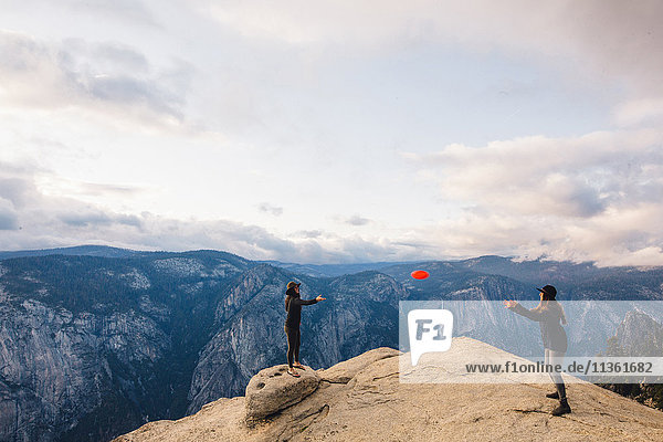 Junge Frau spielt mit Flying Disc auf dem Gipfel eines Berges mit Blick auf den Yosemite National Park  Kalifornien  USA