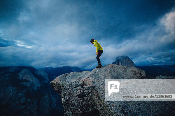 Mittelgroßer erwachsener Mann  der am Gipfel eines Berges steht und über den Rand schaut  Yosemite National Park  Kalifornien  USA
