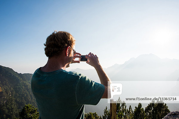Rear view of man taking photograph of mountains  Passo Maniva  Italy