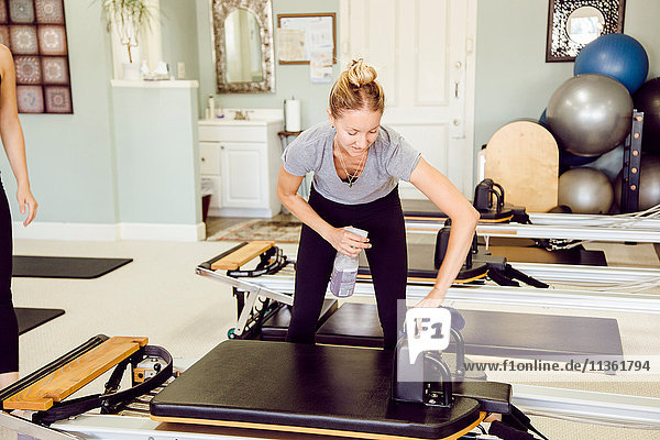 Frauen im Fitnessstudio reinigen Pilates-Reformer
