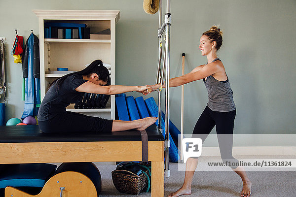 Woman and personal trainer using pilates reformer