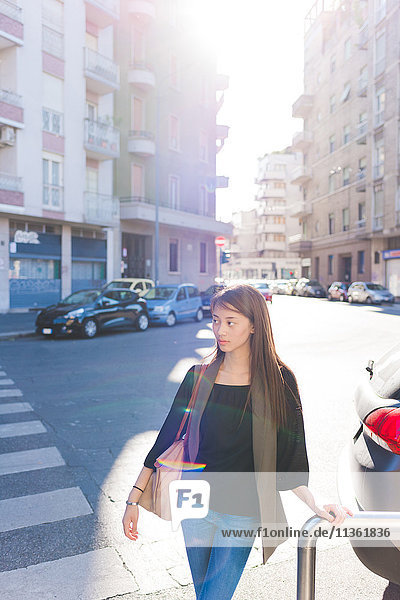 Young woman standing on street watching over her shoulder