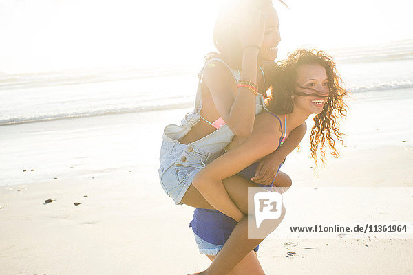 Young woman piggybacking female friend on beach  Cape Town  South Africa