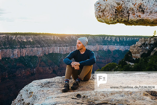 Man sitting on edge of Grand Canyon  Arizona  USA