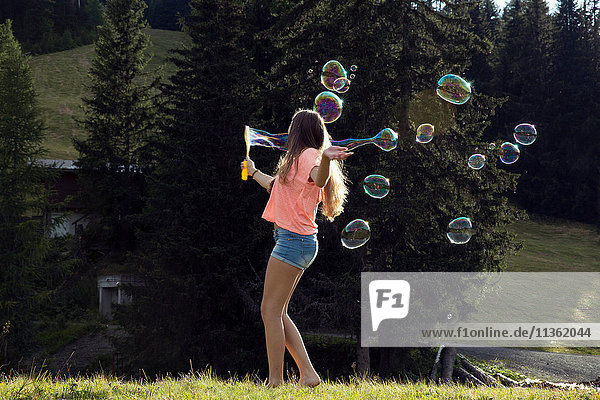 Junge Frau  die im Feld Seifenblasen bläst  Sattelbergalm  Tirol  Österreich