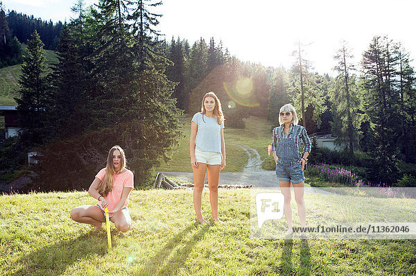Porträt von drei erwachsenen Freundinnen im Feld stehend und kauernd  Sattelbergalm  Tirol  Österreich