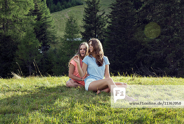 Zwei junge Freundinnen auf dem Feld sitzend  Sattelbergalm  Tirol  Österreich