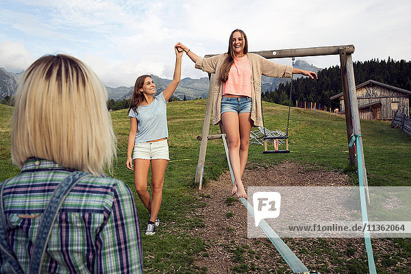 Drei erwachsene Freundinnen balancieren auf Slackline in den österreichischen Alpen  Sattelbergalm  Tirol  Österreich