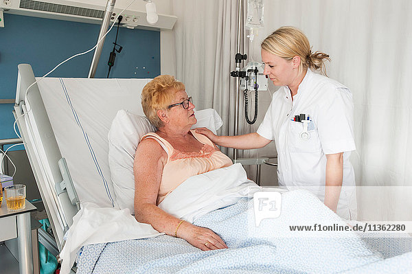 Nurse tending to patient in hospital bed