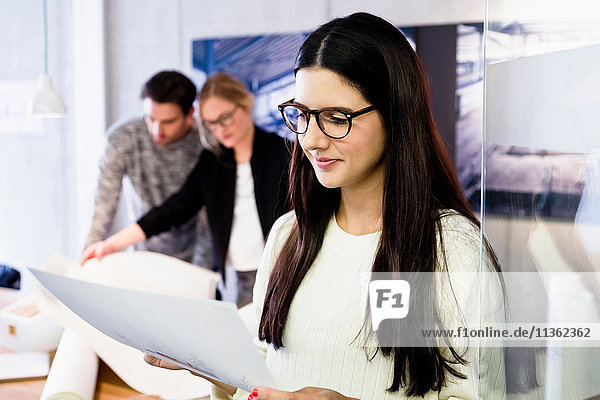 Young woman in office holding paperwork smiling