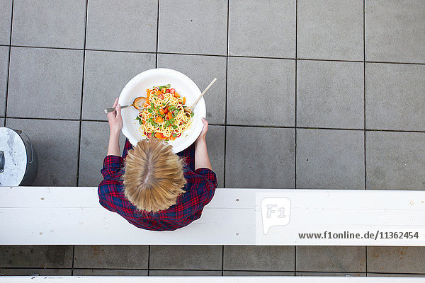 Overhead view of woman holding serving bowl of pasta