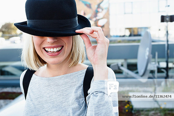 Portrait of blonde haired woman wearing hat over eyes smiling