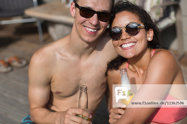 Porträt eines Paares  das Bierflaschen hält und lächelnd in die Kamera schaut