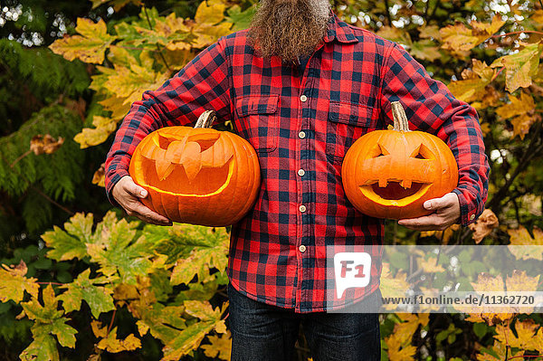 Mature man holding carved pumpkins
