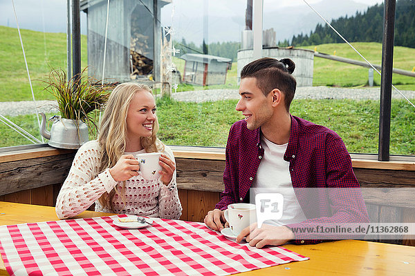 Junges Paar trinkt Kaffee und unterhält sich im Café