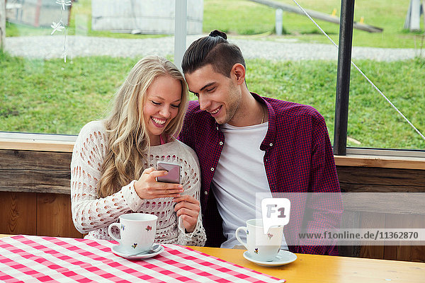 Junges Paar betrachtet Smartphone-Update im Cafe