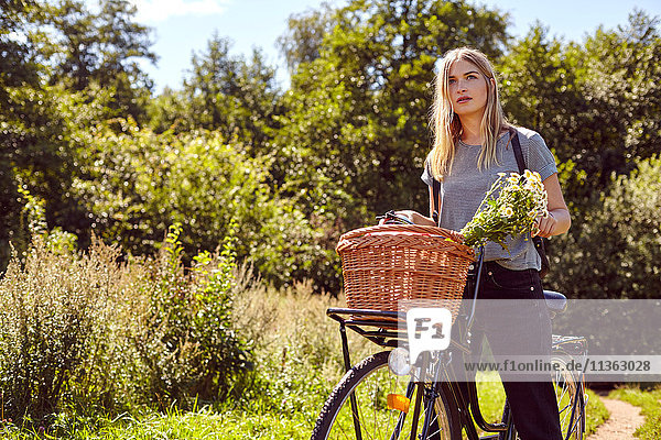 Porträt einer jungen Frau auf dem Fahrrad  die vom ländlichen Feldweg aus blickt