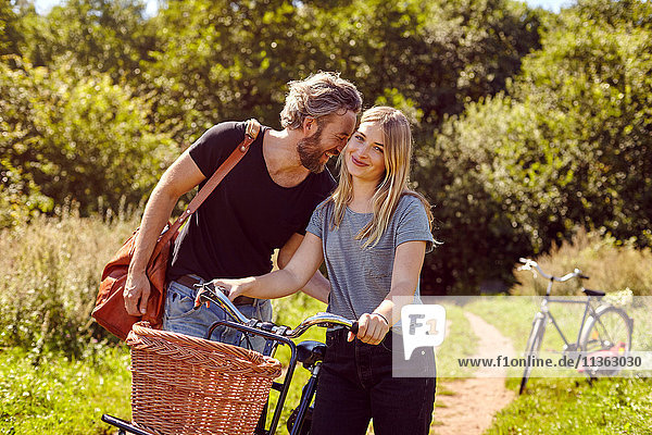 Porträt eines Paares mit lachenden Fahrrädern auf ländlichem Feldweg